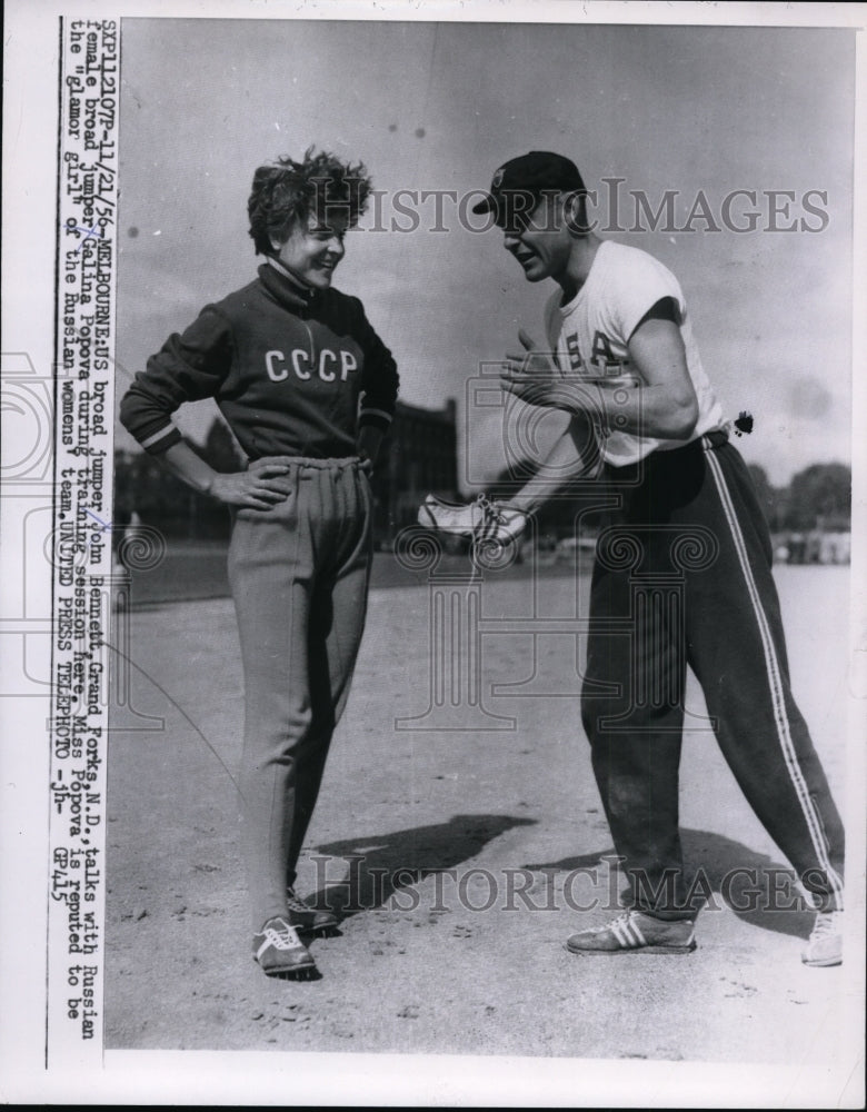 1956 Press Photo US broad jumper John Bennett talks with Russian jumper Popova - Historic Images