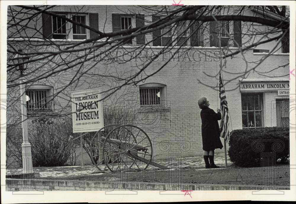 1973 Press Photo Woman hangs an American flag at Abraham Lincoln's museum home - Historic Images