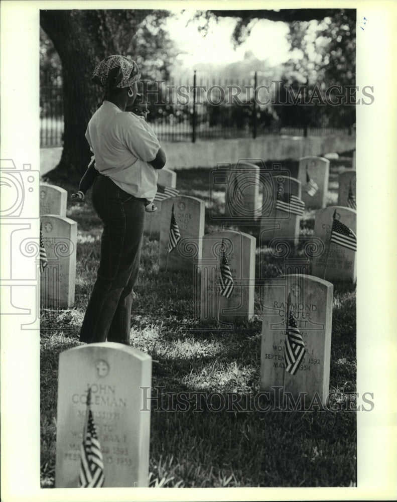 Load image into Gallery viewer, Press Photo Woman holding baby stands at gravestone at Alabama cemetery
