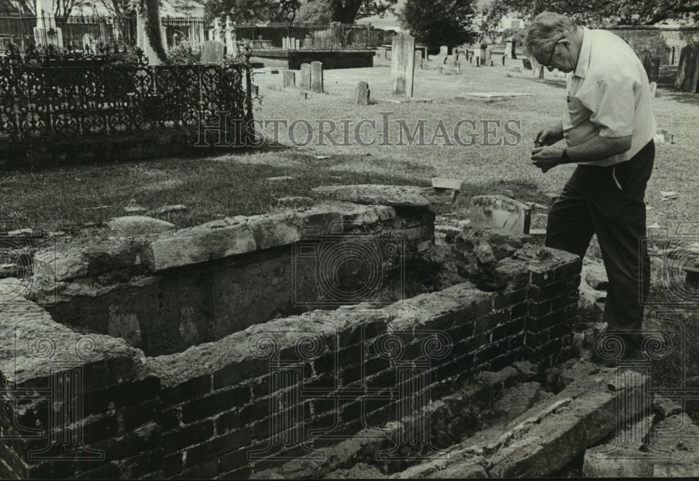 1989 Press Photo Man inspecting at damaged grave at a cemetery, Alabama- Historic Images