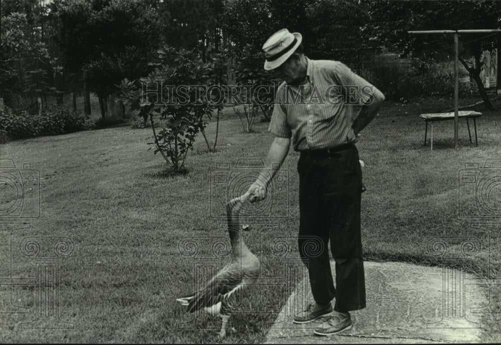 1987 Press Photo Man feeds duck in Gateswood, Alabama - Historic Images