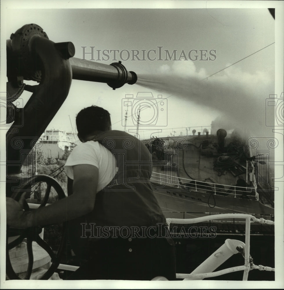 1965 Press Photo Fireman on fire boat sprays listing Arctic Reefer in Alabama- Historic Images