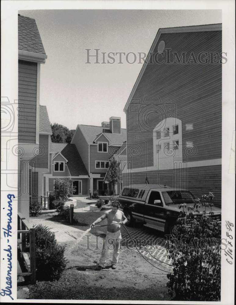 1991 Press Photo Man waters plants at Greenwich Court condos - ctga07778- Historic Images