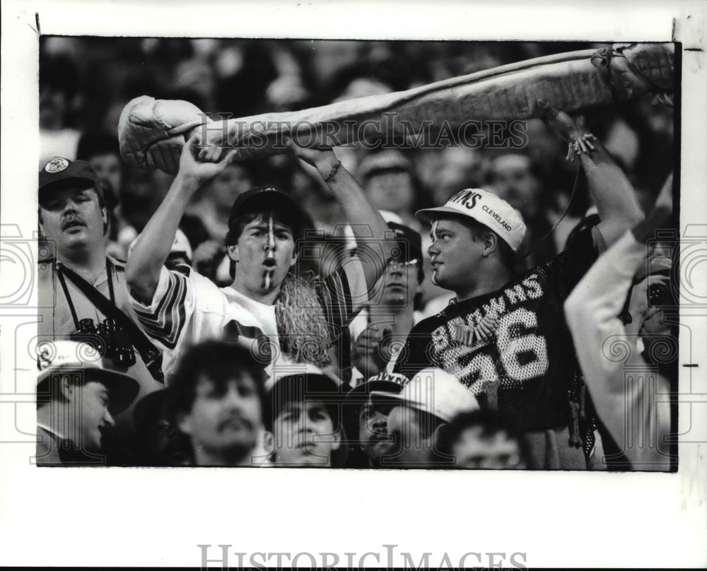 1988 Press Photo Two fans hoist a giant rawhide dog bone in the bleachers- Historic Images