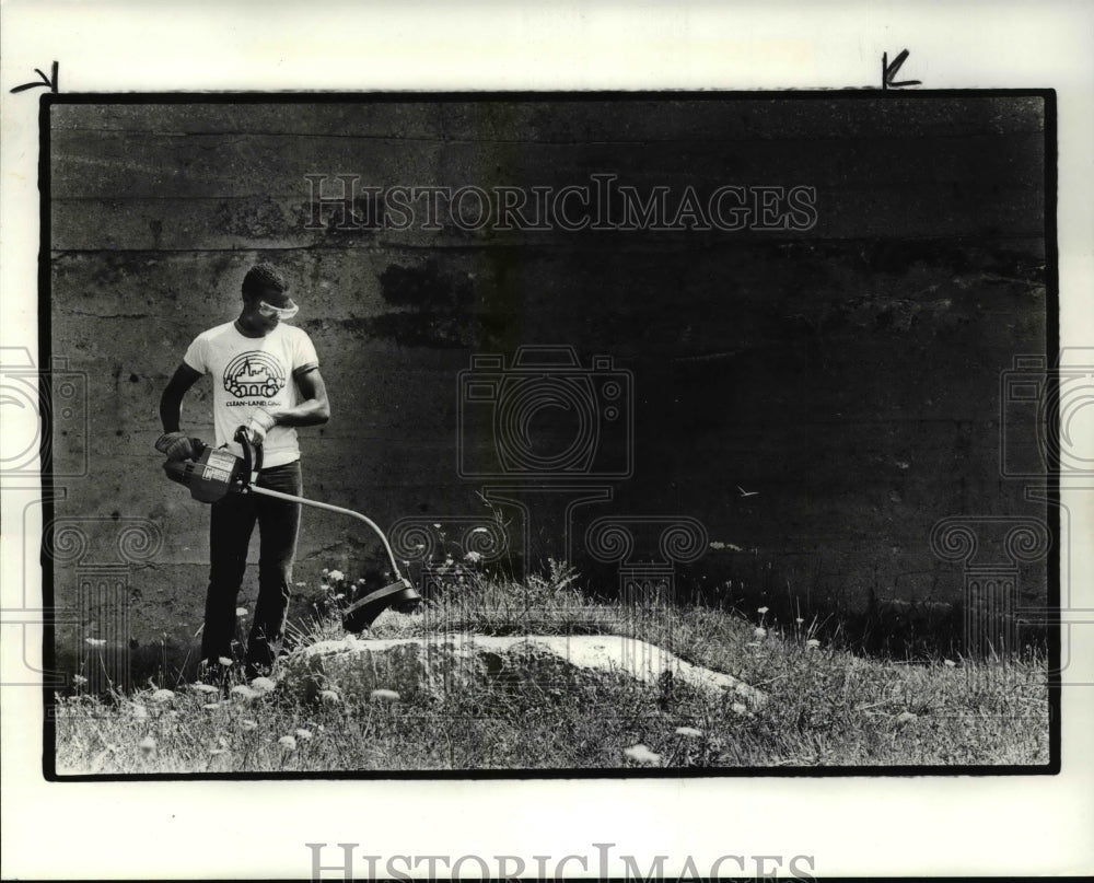 1985 Press Photo Pernell Hobley wack some weeds at E.55th and Chester.- Historic Images