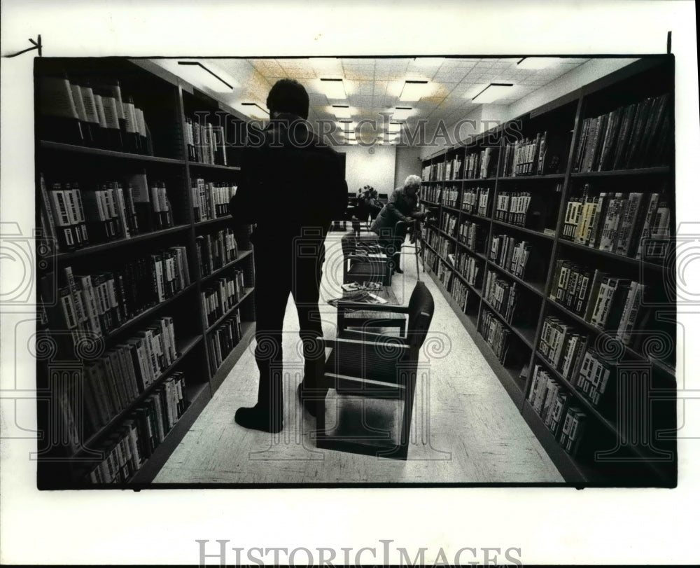 1984 Press Photo Don Smith picking up books in the Library- Historic Images