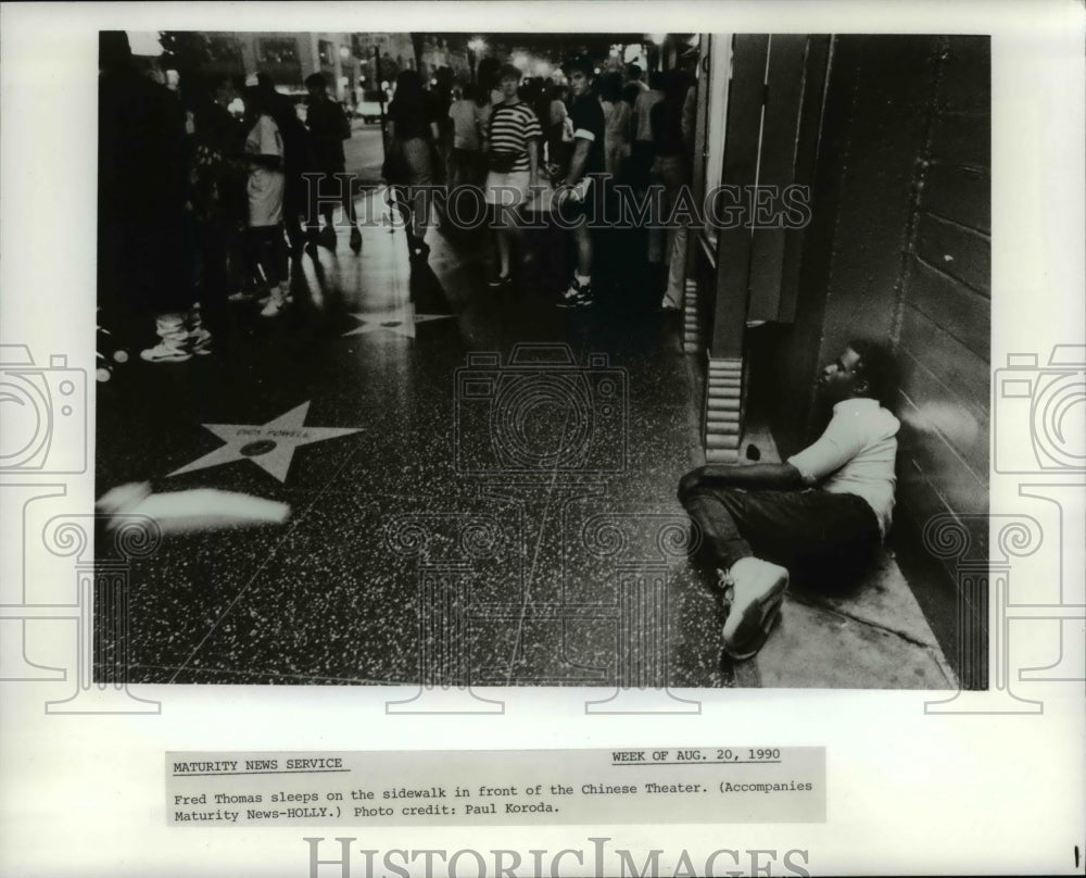 1990 Press Photo Fred Thomas sleeps on the sidewalk in front of the Chinese - Historic Images