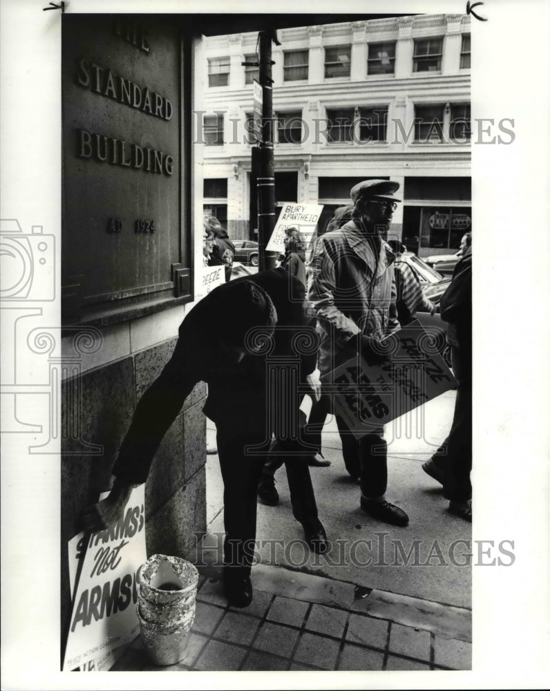 1985 Press Photo A late arrival picks up his sign as a 100 others march protest- Historic Images