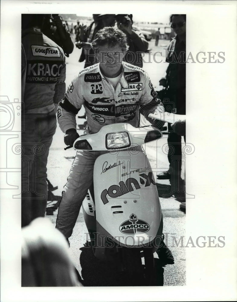 1988 Press Photo Mario Andretti uses a motor bike to run up and down the pit- Historic Images