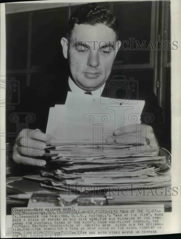 1943 Press Photo Tom Hamilton runs over papers for planning football programs- Historic Images