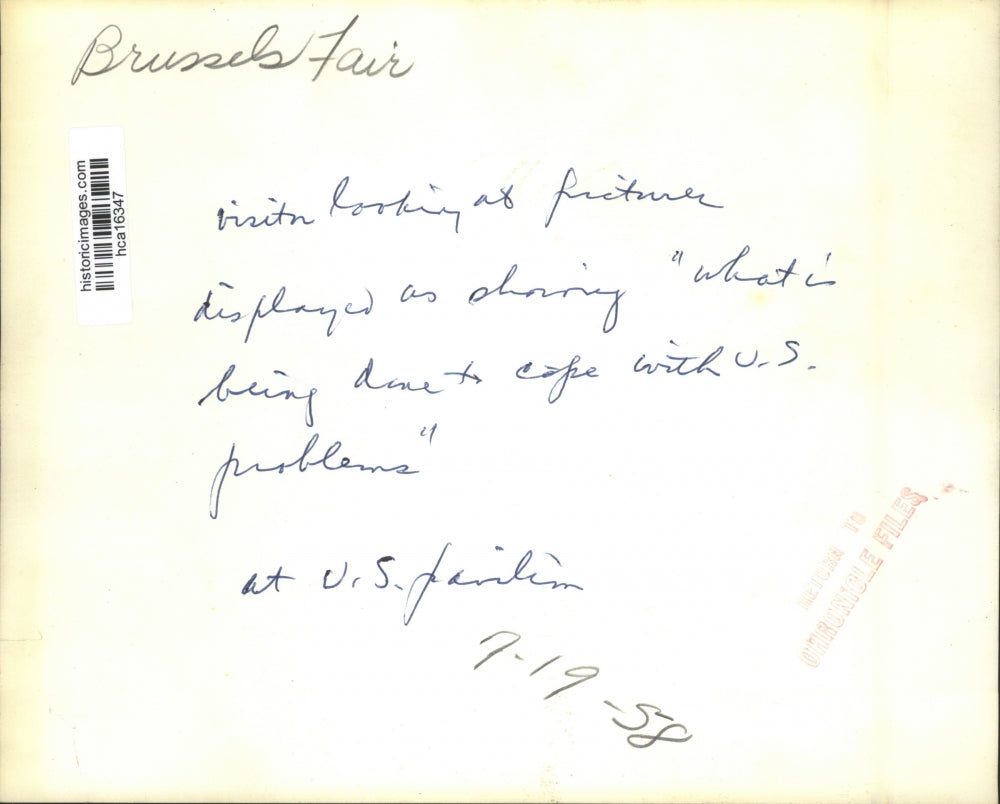 1958 Press Photo Brussels Fair Visitor views pictures at U.S. Pavilion