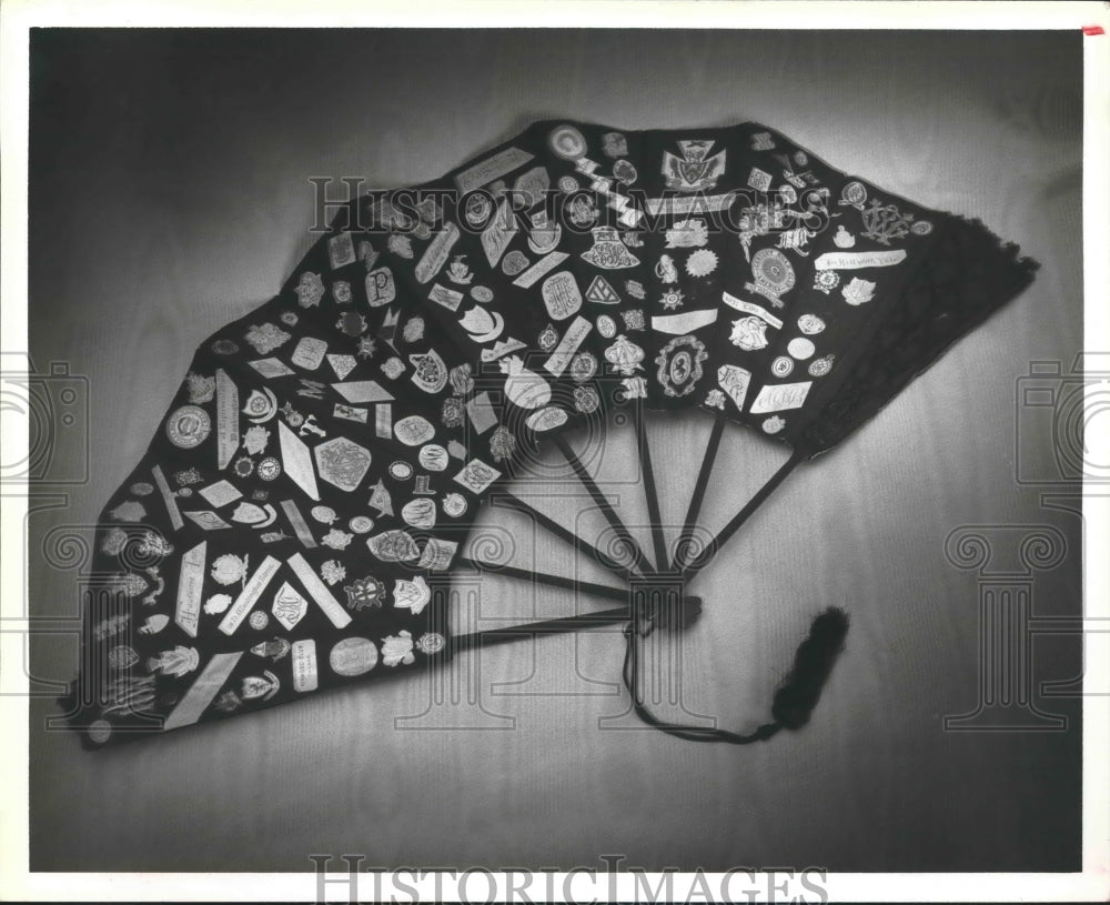 1983 Press Photo Hand fan with college seals, monograms and motto's glued to it
