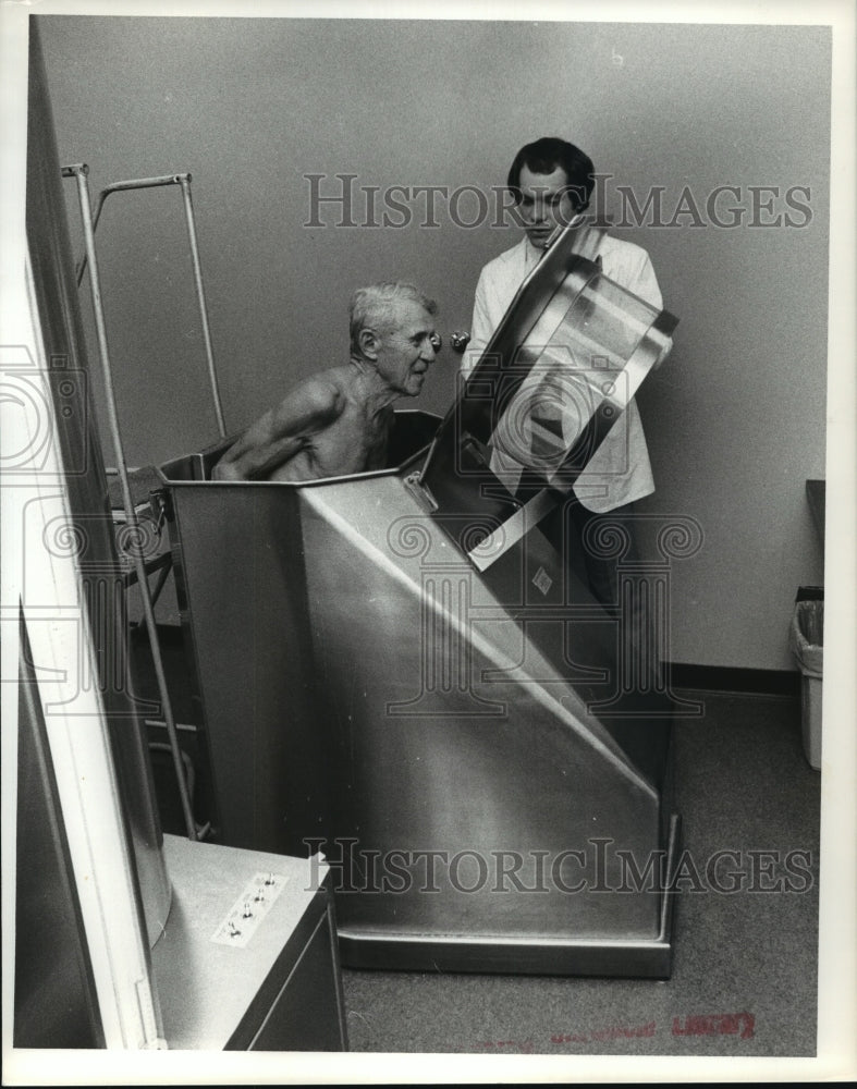 1979 Press Photo Houston Sports Coordinator helps man exit metal chamber- Historic Images