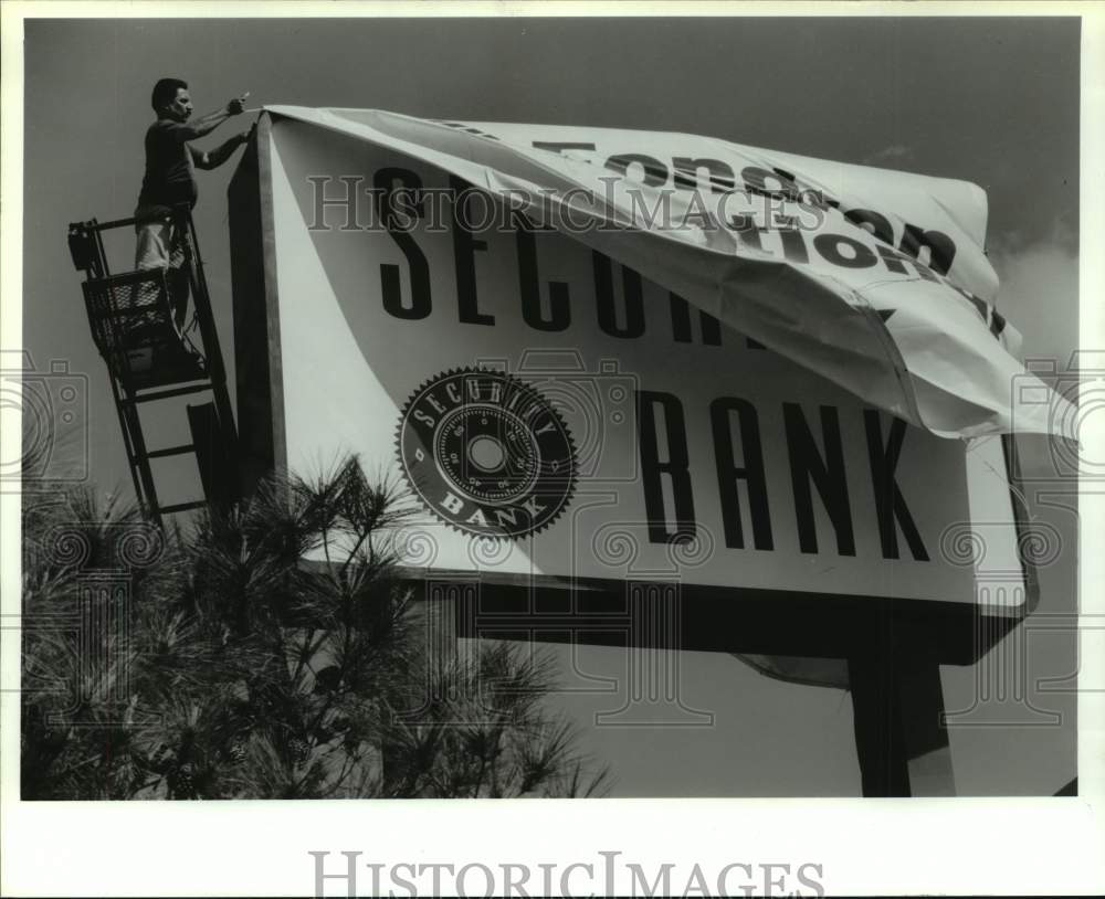 1992 Press Photo State Sign Employee Pete Valdez Hanging Up Security Bank Sign- Historic Images