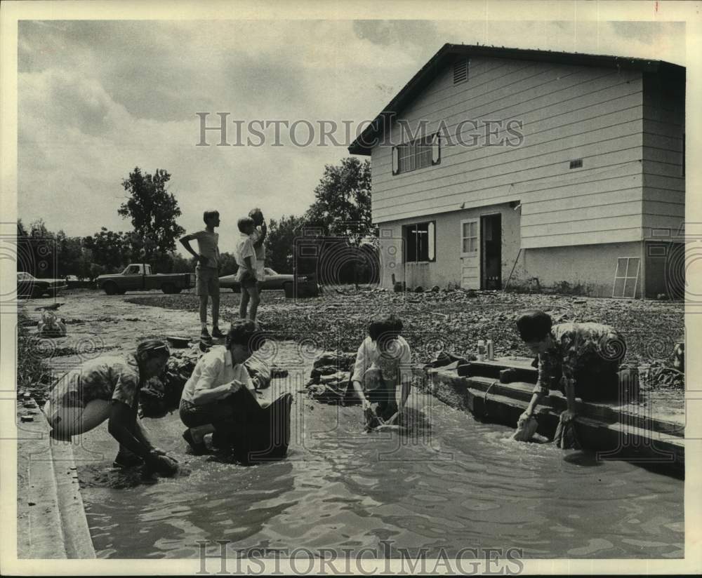 1972 Press Photo Women rinse mud from clothes in flood water - Sequin, Texas