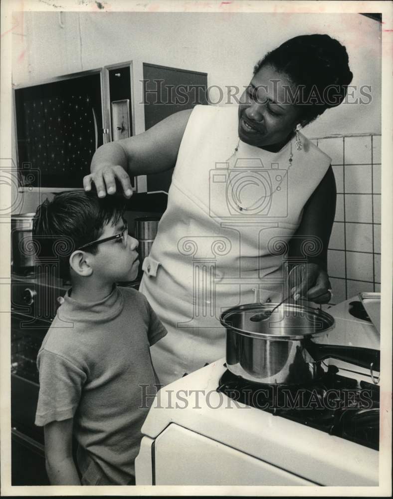 1970 Press Photo Johnnie Hudspeth cooks while little Tony Rodriguez looks on.- Historic Images