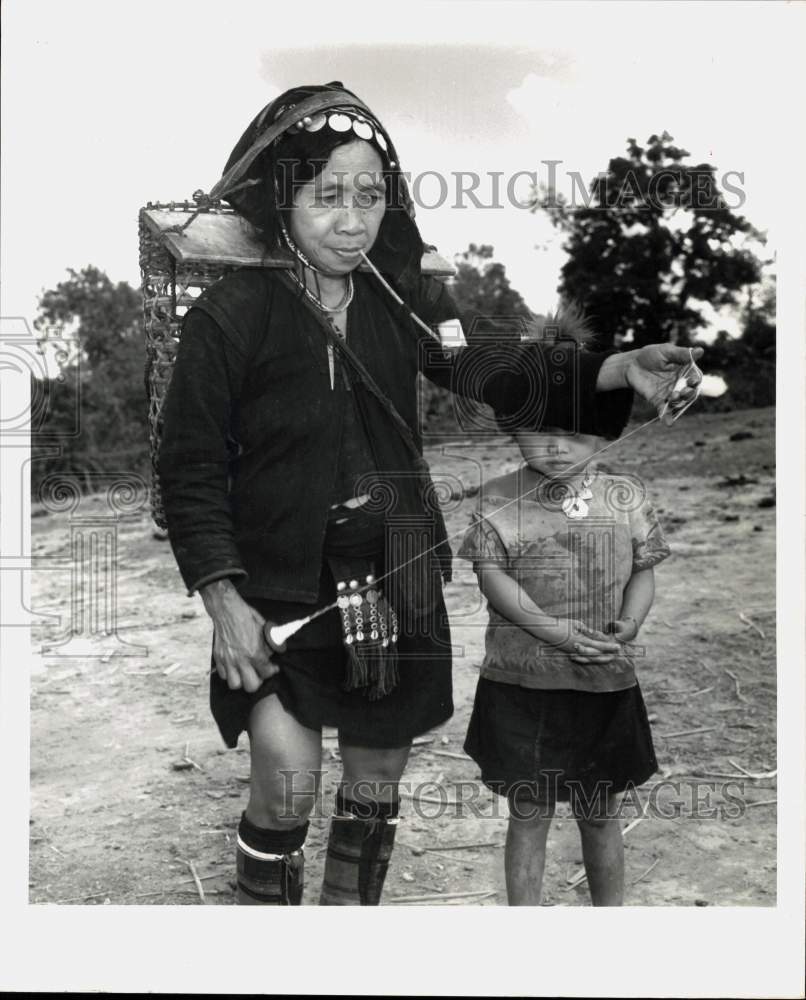 1969 Press Photo Child Watches Akha Tribe Woman Unwind Bamboo Fiber in Thailand