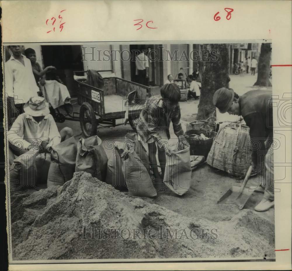 1968 Press Photo Enterprising Vietnamese fill sandbags for sale in Saigon