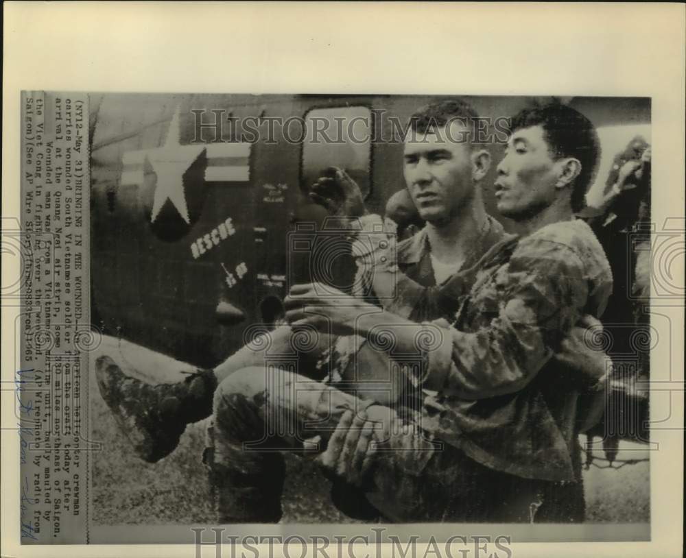 1965 Press Photo U.S. helicopter crewman carries wounded S. Vietnamese soldier