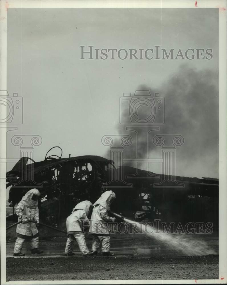 1964 Press Photo Bergstrom Air Force Base firemen spray lingering flame