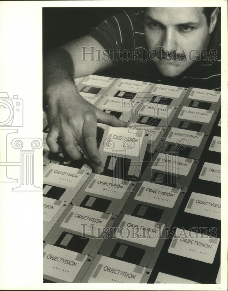 1991 Press Photo Borland employee inspects computer disks, California.- Historic Images