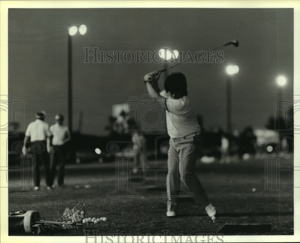 Press Photo Golfer practices his drive under lights at Houston driving range.- Historic Images