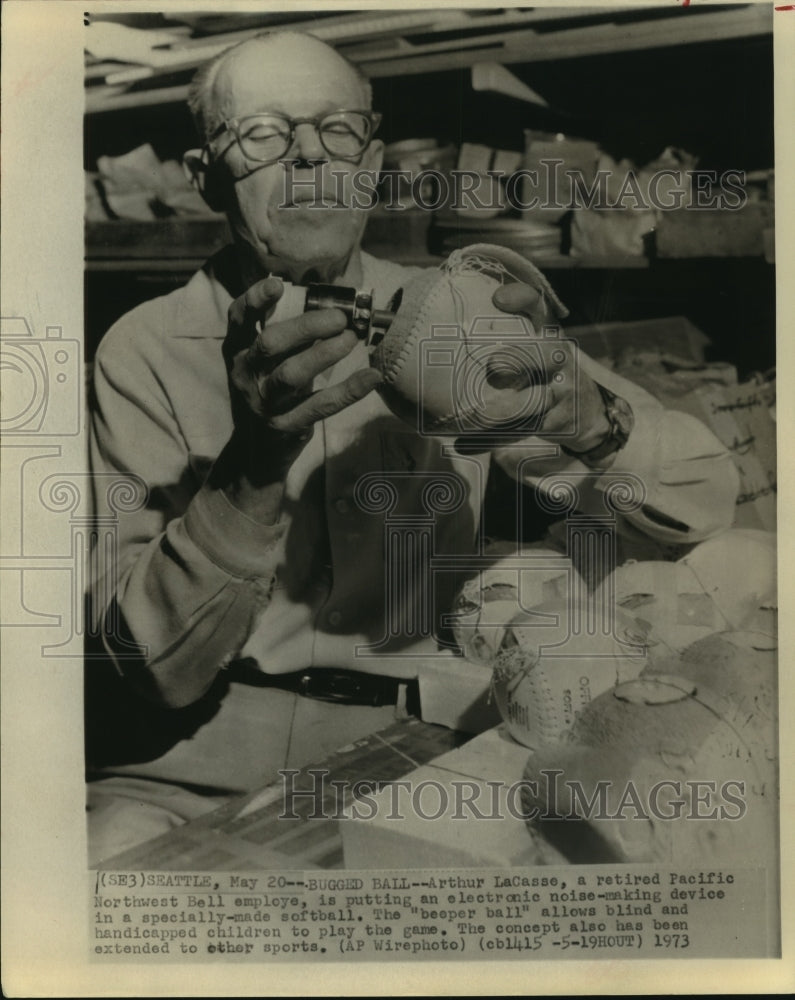 1973 Press Photo Arthur LaCasse puts noise-making device in special softball.- Historic Images