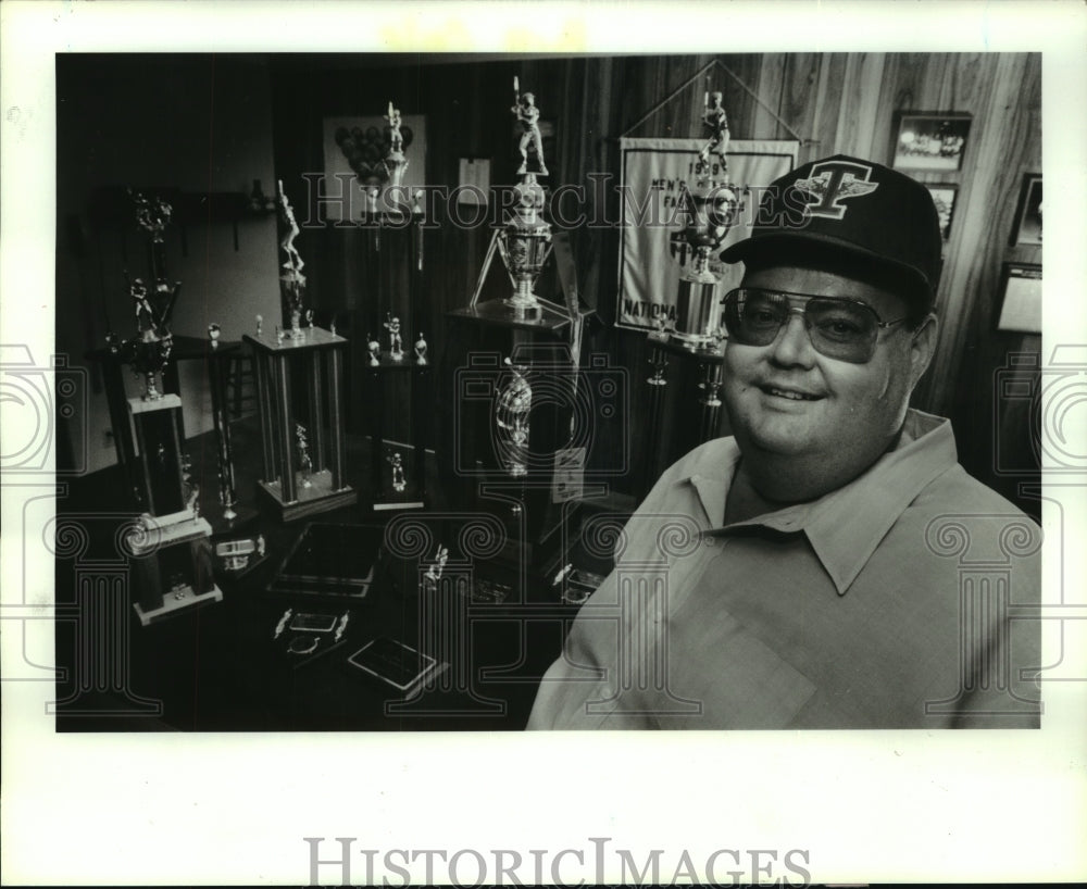 1990 Press Photo Softball coach Bill Cole stands among trophies his teams won.- Historic Images