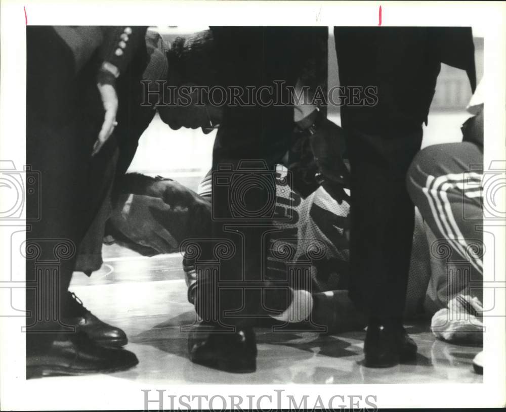 1990 Press Photo Akeem Olajuwon is tended to after hitting his head on the floor- Historic Images