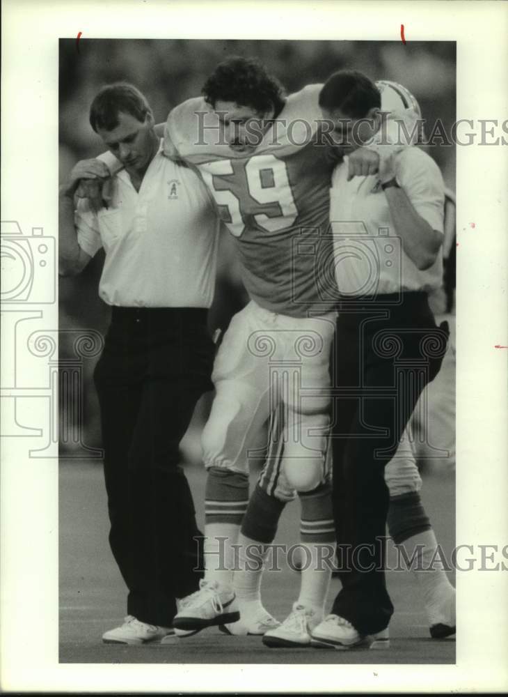 1987 Press Photo Oilers linebacker John Grimsley is helped off field by trainers- Historic Images