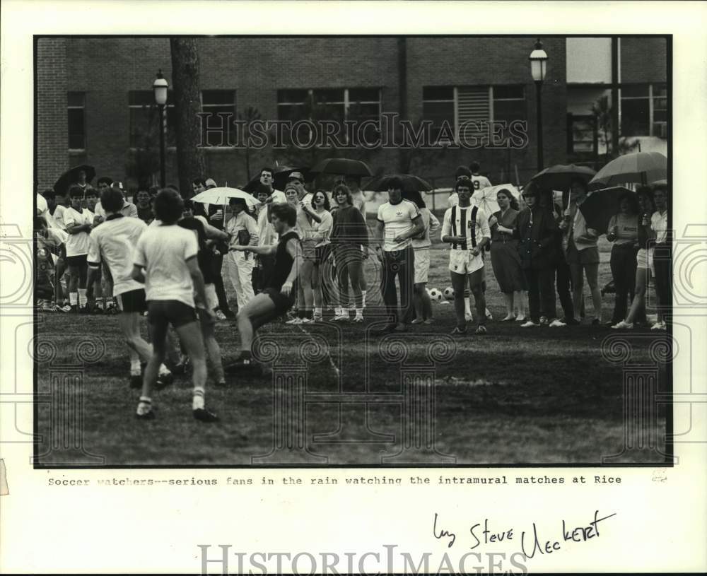 1984 Press Photo Serious soccer fans watch match in rain at Rice University- Historic Images