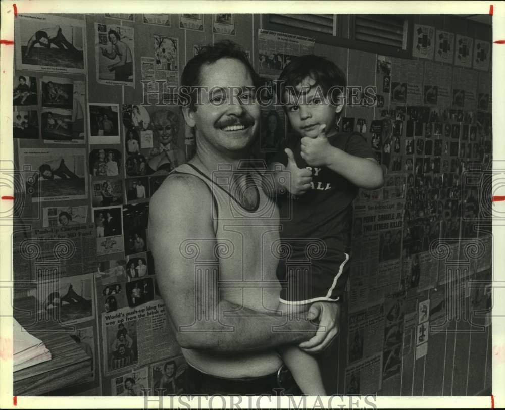 1980 Press Photo World push-up champion Henry Marshall holds son Henry.- Historic Images