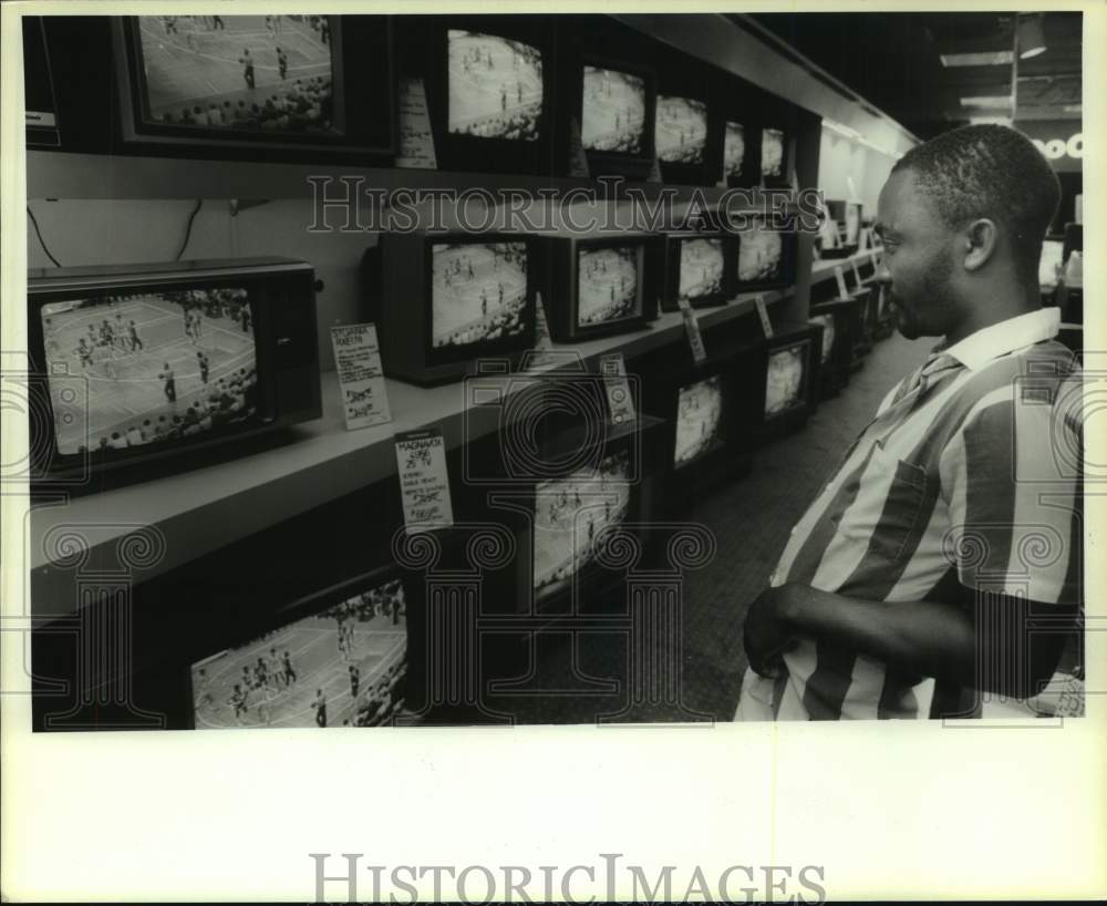 1986 Press Photo Saturday Ologhoejebi watches Houston Rockets basketball on TV's- Historic Images