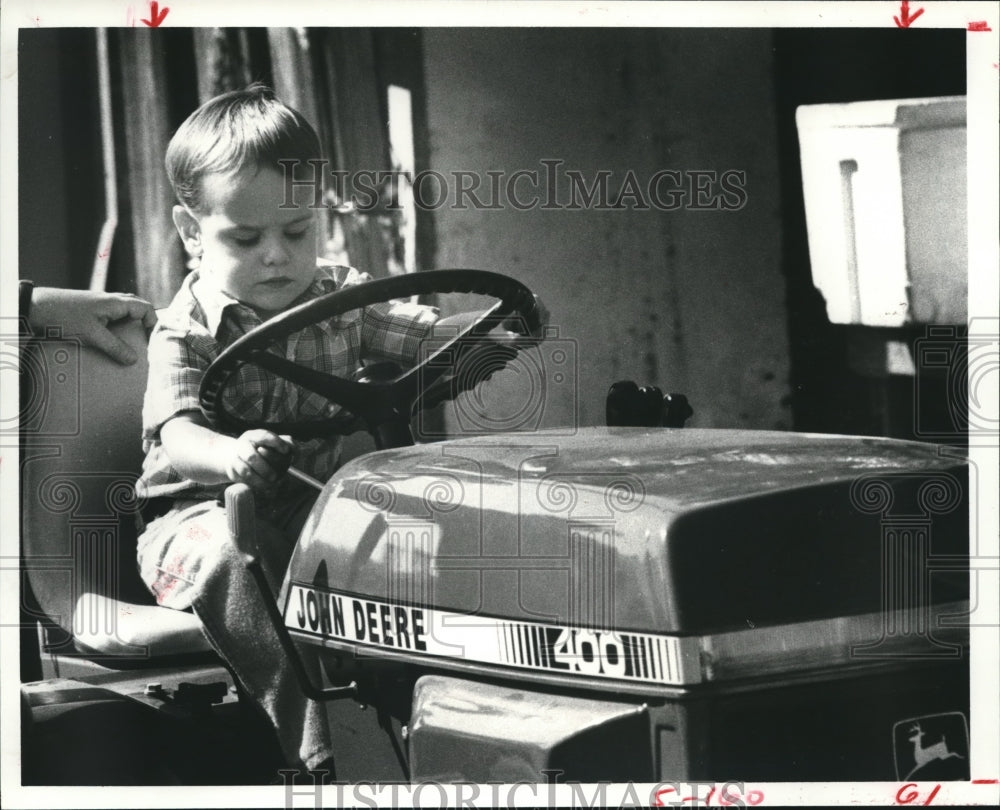 1980 Press Photo Gregory Wheeler Examines a Tractor at Brazoria County Fair, TX- Historic Images