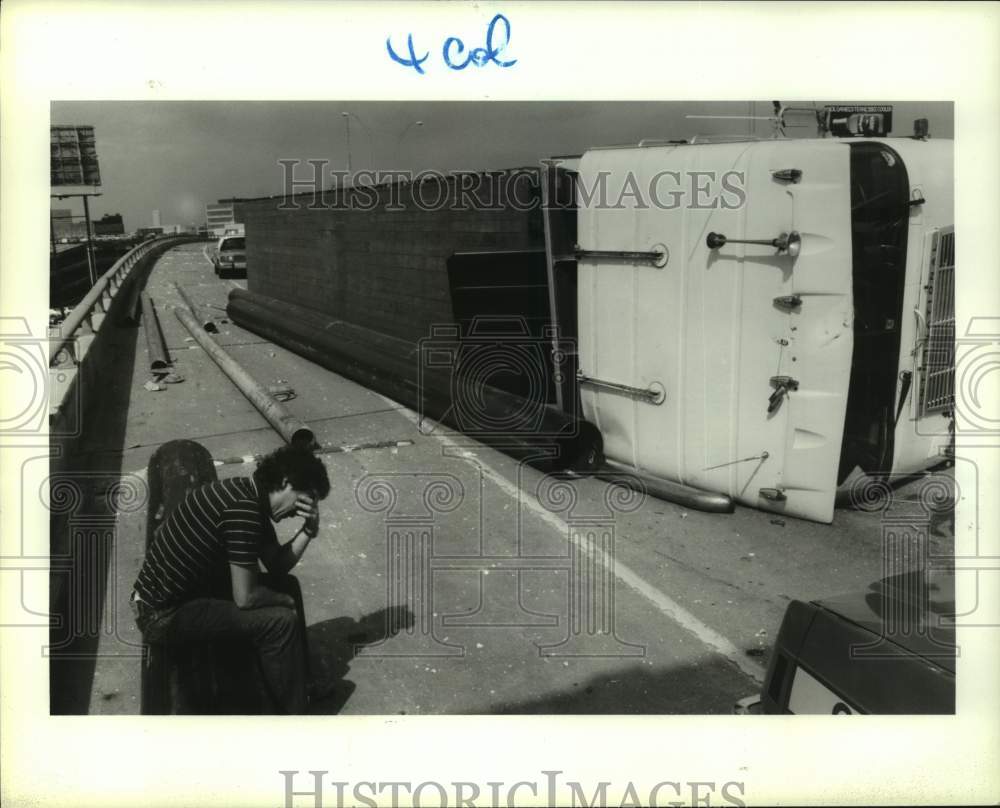 1987 Press Photo Driver James Barrick sits by his overturned truck in Houston- Historic Images