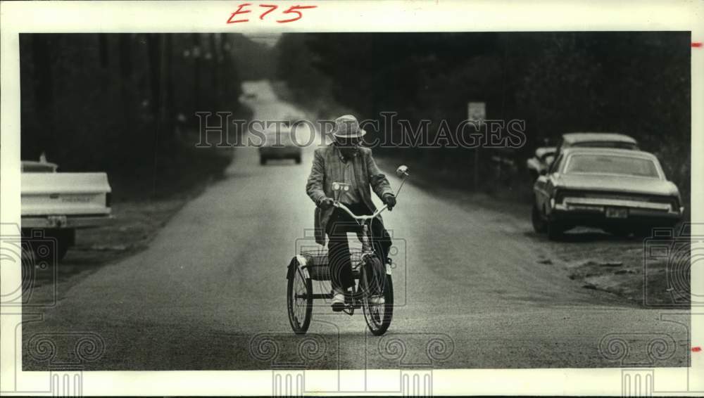 1983 Press Photo Carl McMillion Rides Tricycle down a Main Street in Tamina, TX