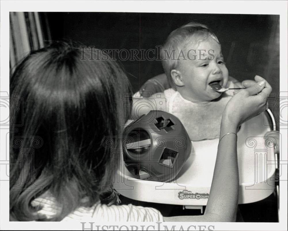 1983 Press Photo Girl Feeding Infant in Walker - hpa10248- Historic Images