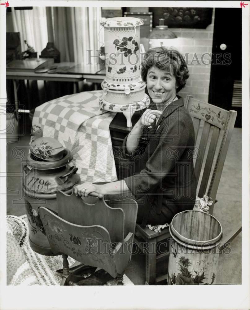 1967 Press Photo June Hagen, artist, sits amid country style painted articles.- Historic Images