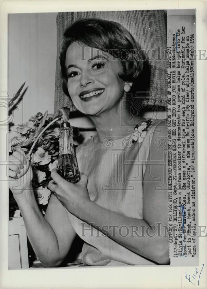 1964 Press Photo Olivia de Havilland, actress, shows perfume atomizer.- Historic Images