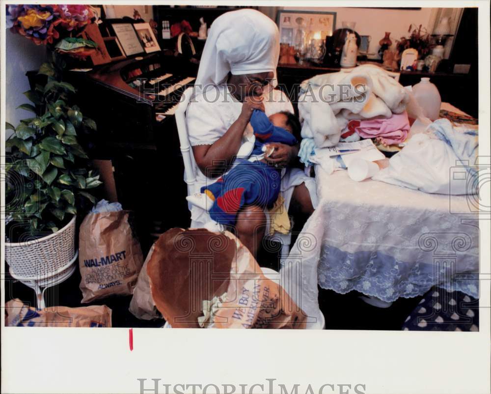 Press Photo Sister Helen Gay carrying baby Isaac as she sorts out family clothes- Historic Images