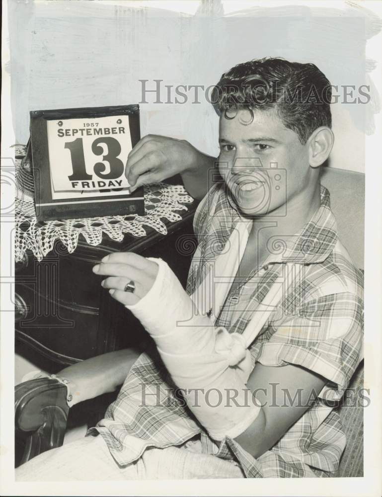 1957 Press Photo Ronny Osburn with injured arm show calendar with Friday 13th.- Historic Images