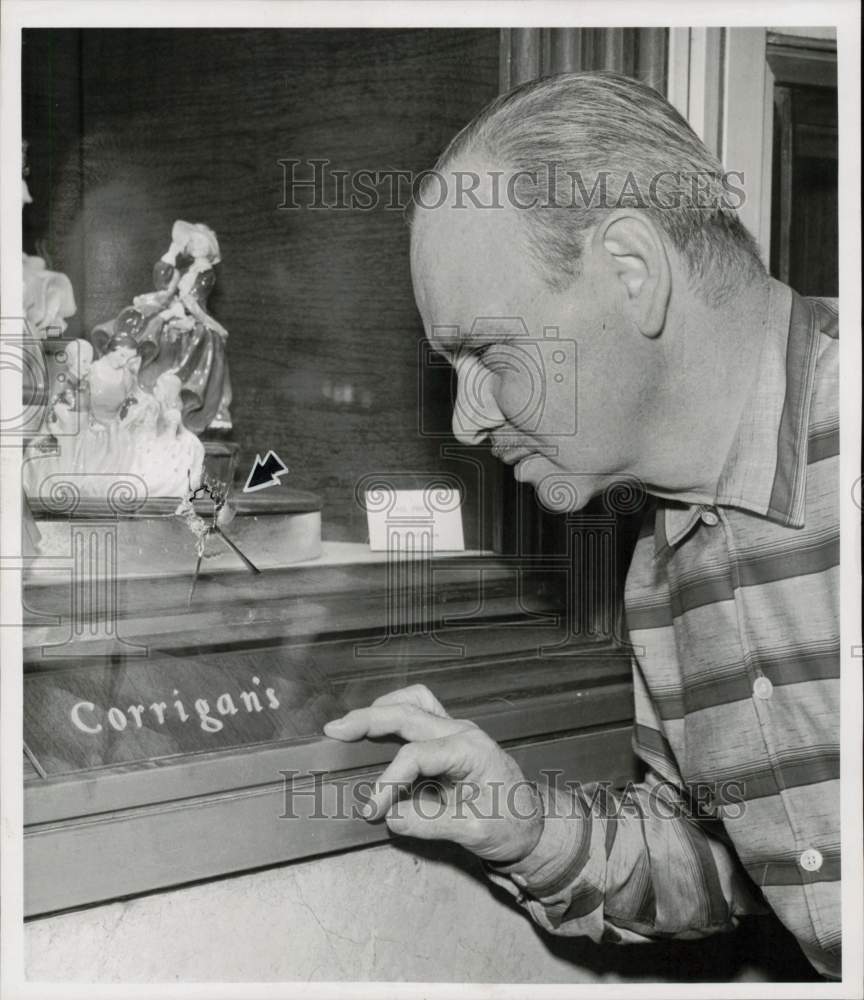 1957 Press Photo Al Gatto, Corrigan display director examines theft area.- Historic Images