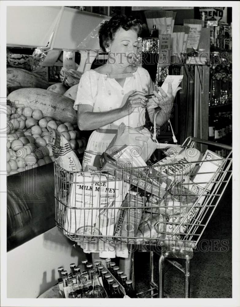 1961 Press Photo Mrs. Horace Pounds checks grocery list while shopping.- Historic Images