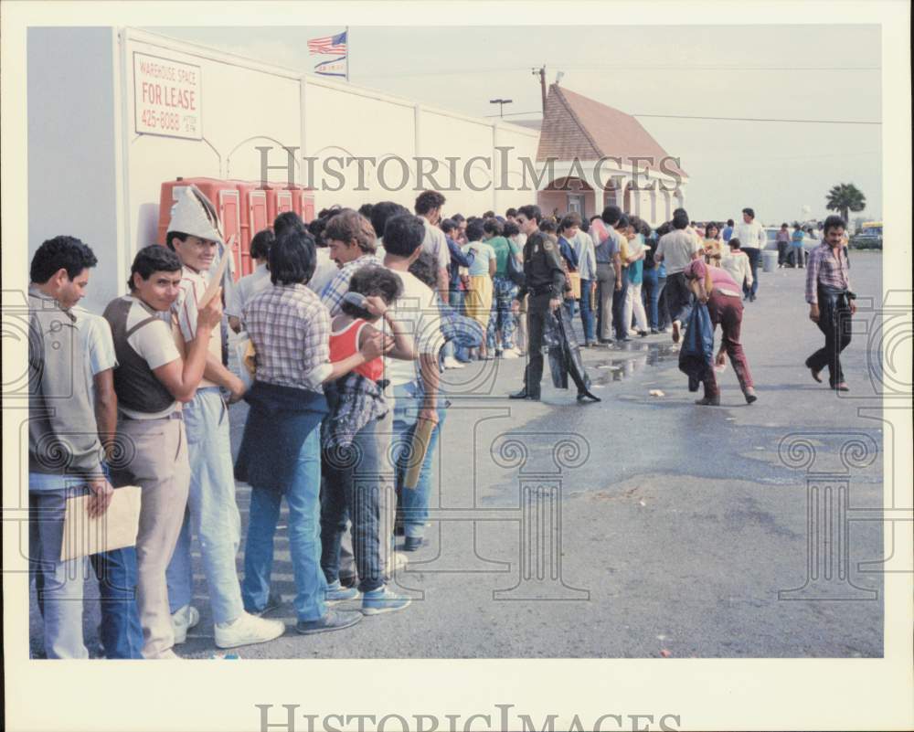 1989 Press Photo Officer hands out trash bags to illegals at INS office, Texas- Historic Images