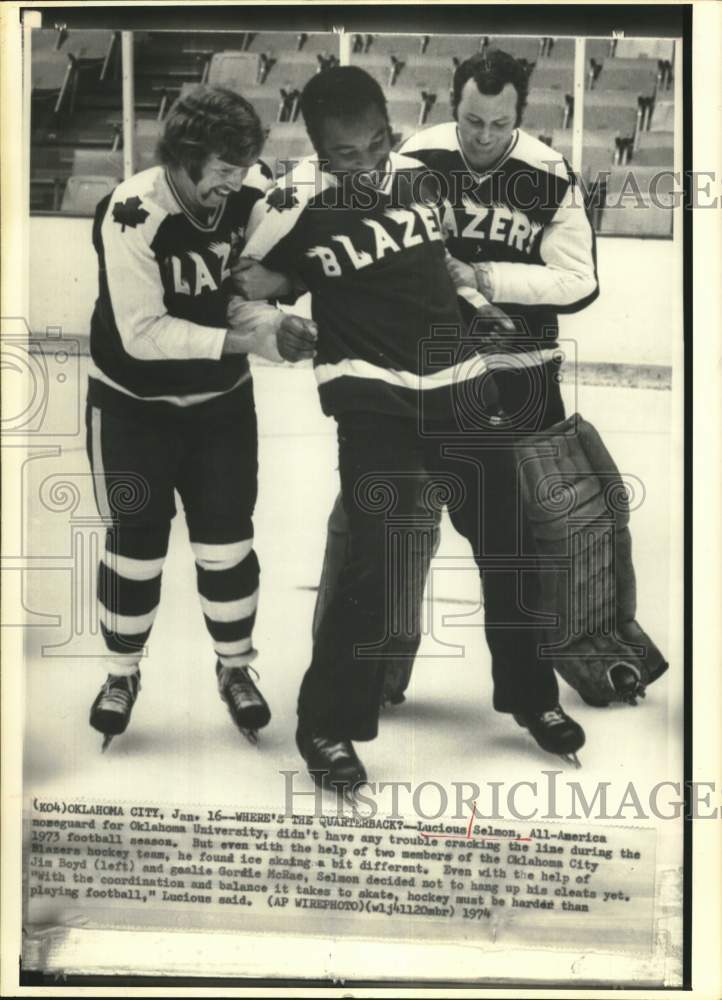 1974 Press Photo Football star Lucious Selmon aided by hockey players in OK.- Historic Images