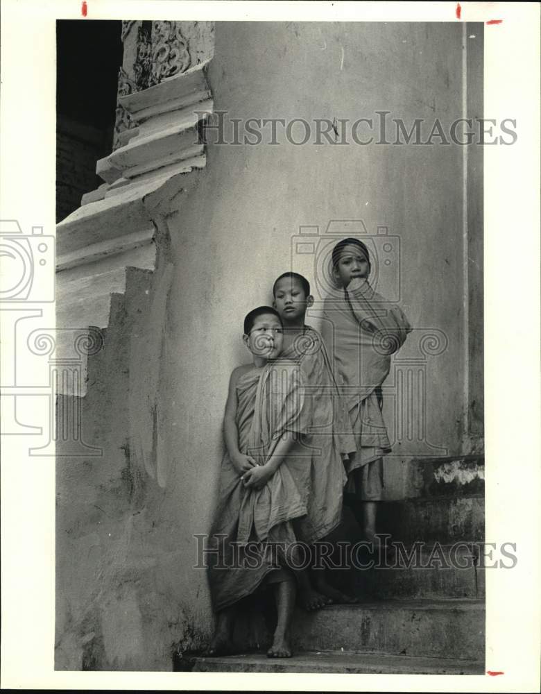 1982 Press Photo Young Monks watch from temple steps in Bangkok, Thailand- Historic Images