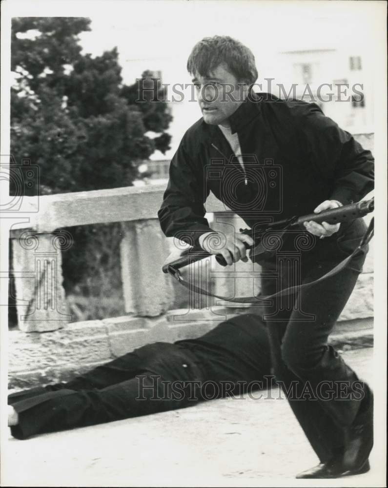 1975 Press Photo Actor Robert Vaughn runs past a body in an action scene- Historic Images