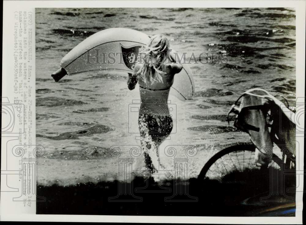 1973 Press Photo Woman Splashes into Lake Harriet with Banana Raft, Minnesota- Historic Images