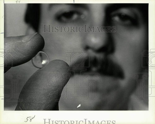 1984 Press Photo Tom Curteman holds a gas-permeable contact lens. - lra06794- Historic Images