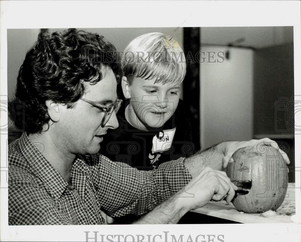 1990 Press Photo Gene Novi carves a pumpkin while son Jovi looks on - lra15143- Historic Images